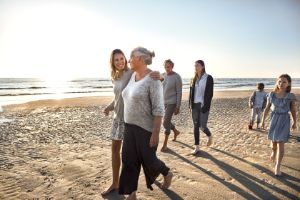 Familie spaziert mit mehreren Generationen am Strand entlang. 