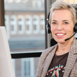 Mitarbeiterin aus dem Kundenservice telefoniert und lächelt.