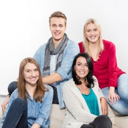 4 fröhliche junge Menschen sitzen auf einem Sofa.