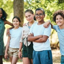 5 Kinder sind zusammen draußen und umarmen sich.