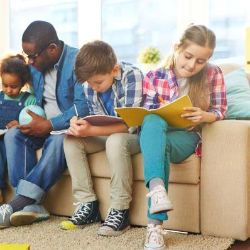 Ein Lehrer sitzt mit Kindern auf dem Sofa.