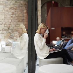 Frau trinkt im Cafe vor dem Laptop