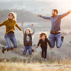 Eine Familie steht auf einer Wiese und springt in die Luft.