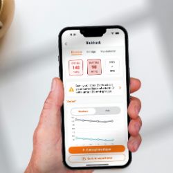 Eine Hand hält ein Handy, auf dem die manoa App geöffnet ist.