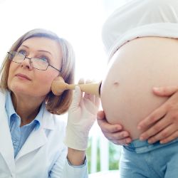 Babybauch wird bei einer Untersuchung abgehoert