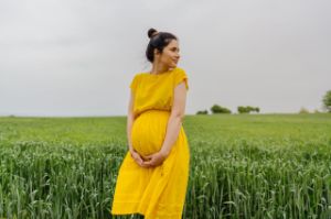 Schwangere steht entspannt im Feld
