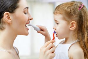 Mutter und Kind putzen sich gegenseitig die Zähne.