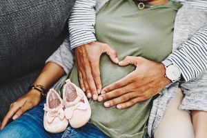 Schwangere mit Partner und Babyschuhen.