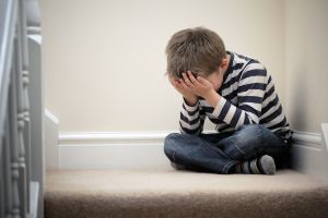 Ein trauriger Junge sitzt auf einer Treppe.