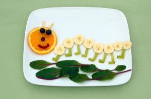 Obst und Gemüse ist auf einem Teller als Raupe angeordnet.