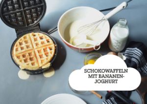 Waffel im Waffeleisen mit Teig in der Schüssel und Teigzutaten auf einem Tisch. Text: Schokowaffeln mit Bananen-Joghut.