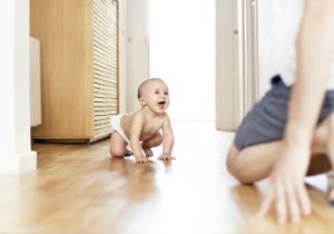 Lachendes Baby krabbelt auf dem Boden.
