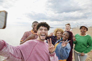 Neue Freunde am Strand machen ein Selfie.