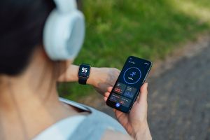 Joggende Frau trackt ihren Puls über einen Fitnesstracker.