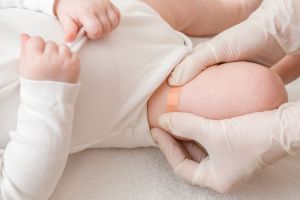 Ein Baby bekommt ein Pflaster nach dem Impfen auf den Oberschenkel geklebt.