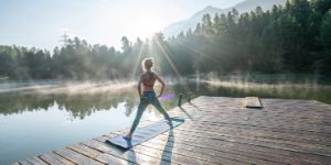 Frau mit Yoga-Matte an einem See