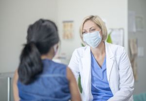Eine Ärztin mit Mund-Nasen-Bedeckung berät eine Frau.