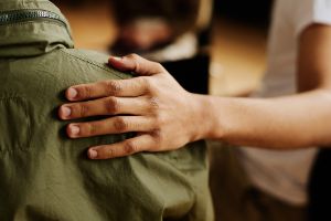 Eine Person legt ihre Hand auf die Schulter einer anderen Person.