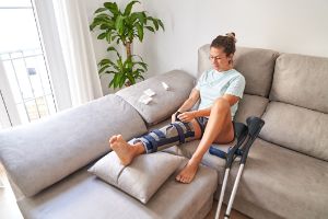 Patientin sitzt nach Meniskustransplantation auf dem heimischen Sofa. 