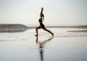 Frau in Yoga-Position am Strand