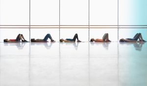 Fünf Frauen liegen mit angewinkelten Beinen auf dem Boden.