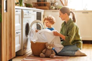 Mutter räumt mit ihrem Kleinkind die Waschmaschine ein.