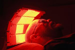 Mann mit Schutzbrille erhält liegend eine Lichttherapie gegen Hautprobleme.