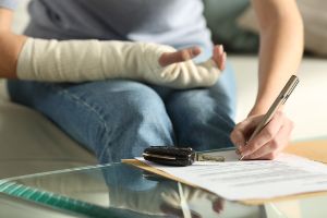 Krankengeldanspruch nach 6 Wochen: Ein junger Mann mit Gipsbein sitzt auf dem Sofa und schaut auf sein Tablet.