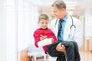 Ein Doktor trägt ein krankes Kind auf dem Arm.
