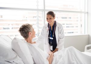 Eine Ärztin spricht freundlich mit einer Patientin im Krankenbett.