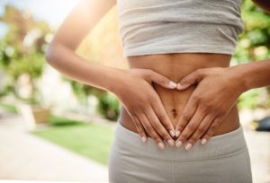 Eine Frau formt mit ihren Händen ein Herz vor ihrem Bauch.