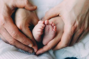 Vater und Mutter formen ihre Handy um die Füße ihre Babys als ein Herz.