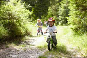 Kleine Kinder fahren auf einem Waldweg Fahrrad.