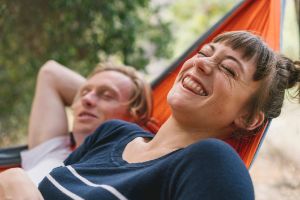 Ein Mann übt lachend in seinem Wohnzimmer auf eine Fitnessmatte.