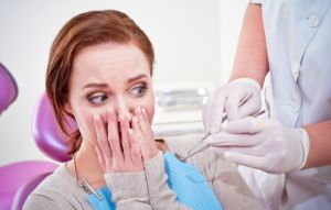 Frau hält die Hände vor ihren Mund aus Angst vor der Zahnbehandlung.