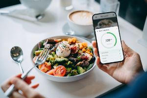 Eine Person trackt auf ihrem Smartphone die Kalorien von ihrem Mittagessen.