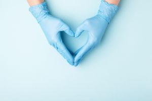 Hände in medizinischen Handschuhen bilden ein Herz.