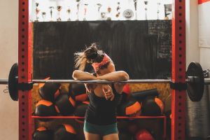 Eine Frau steht Fitnessstudio an einem Gerät und schaut traurig nach unten.
