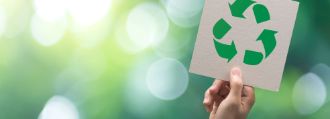 Das Symobol für Recycling wird in die Luft gehalten