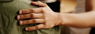 Eine Person legt ihre Hand auf die Schulter einer anderen Person.