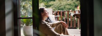 Eine junge Frau sitzt in der Terrassentür und schaut raus.