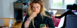 Eine Frau sitzt vor dem Laptop und schaut etwas verzweifelt.