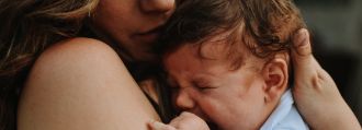 Eine junge Mutter hält traurig ihr Neugeborenes im Arm