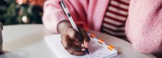 Eine Frau schreibt Neujahresvorsätze auf einen Block.