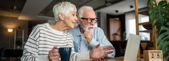Ein älteres Paar sitzt vor dem Laptop und plant Termine.