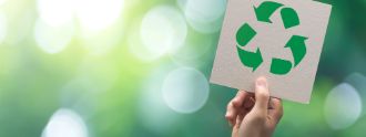 Das Symobol für Recycling wird in die Luft gehalten