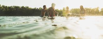 Vier junge Leute baden an einem Sommerabend im See.
