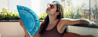 Eine Frau sitzt auf einem Balkon und fächert sich zu.