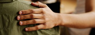 Eine Person legt ihre Hand auf die Schulter einer anderen Person.