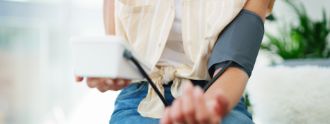 Frau misst mit einem Blutdruckmessgerät ihren Blutdruck.
